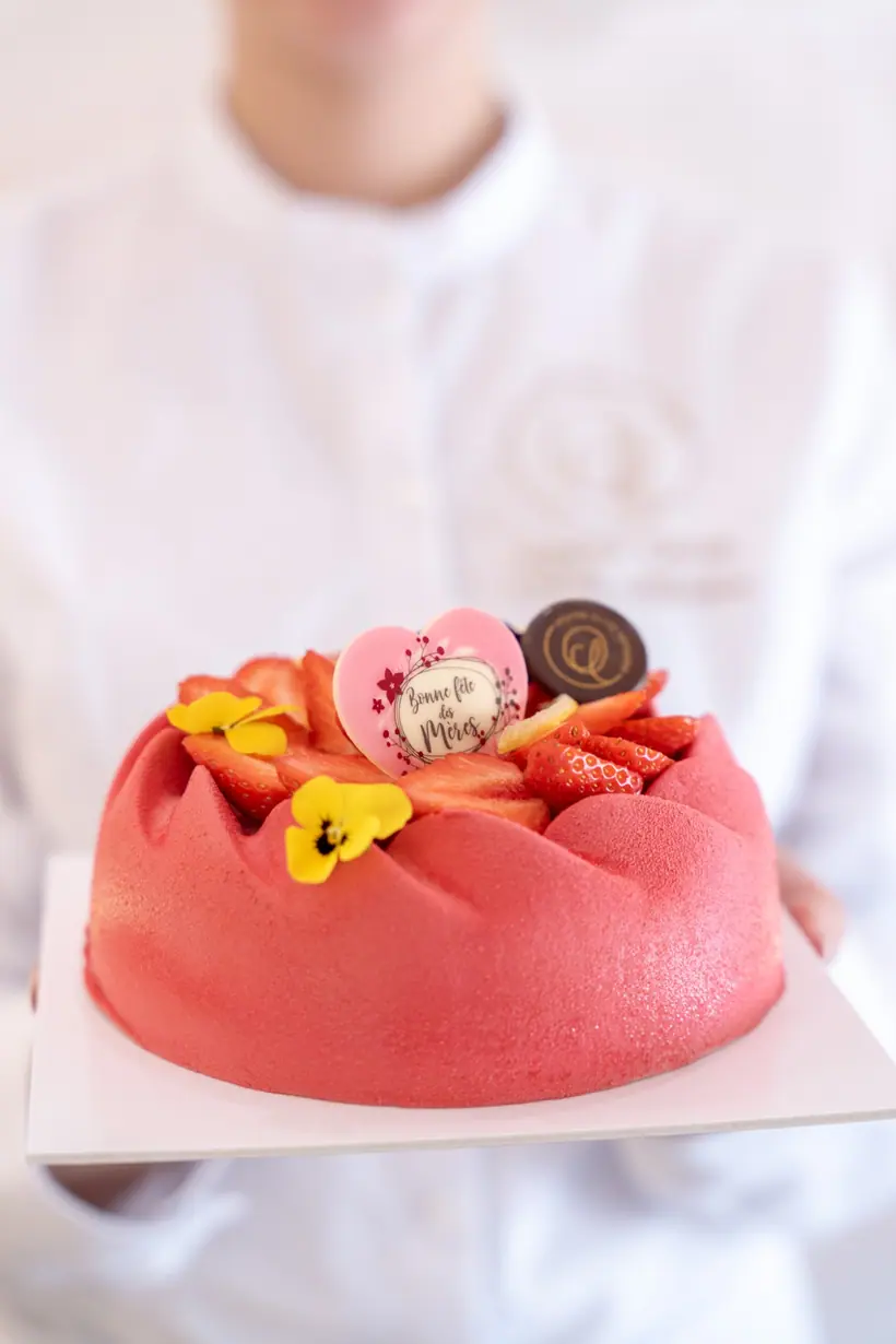 Entremets au velours rouge couronné de fraises fraîches et d'une plaque en chocolat « Bonne fête des Mères »