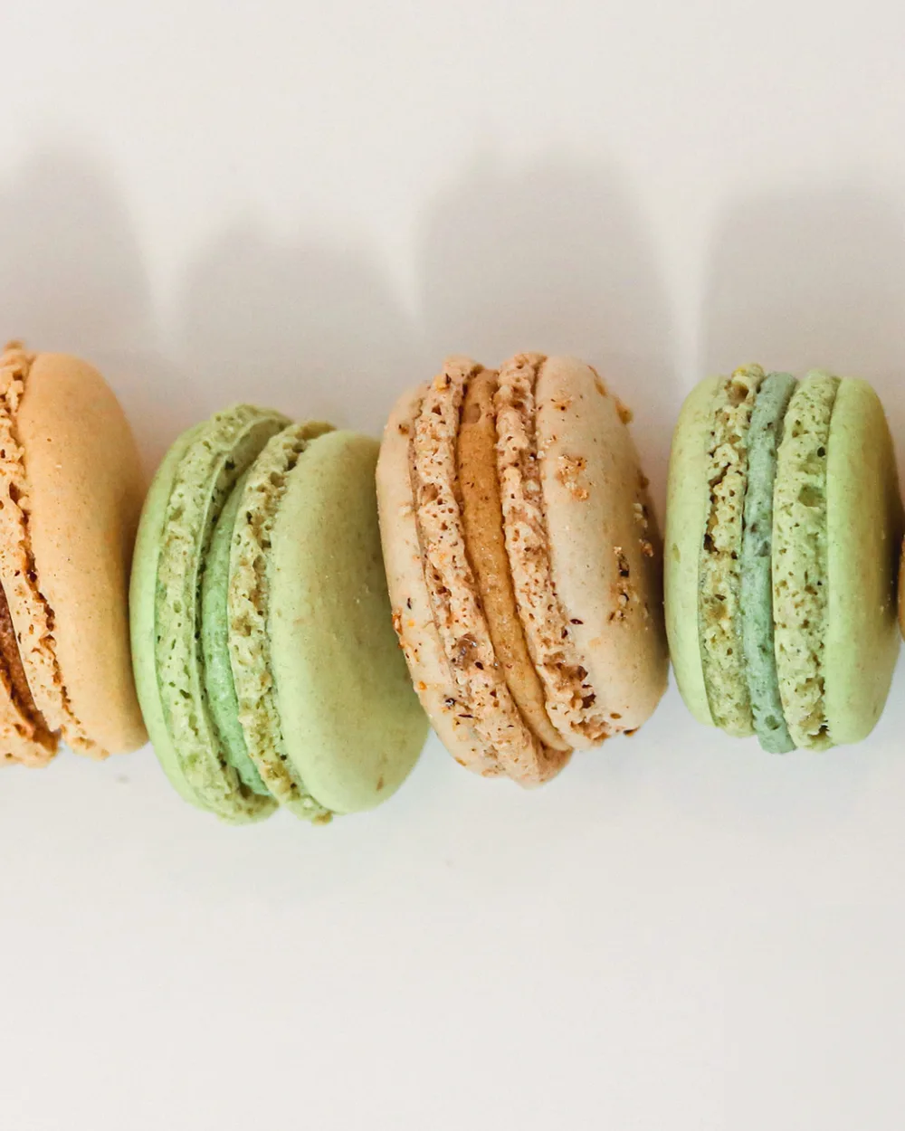 Macarons artisanaux de la Pâtisserie Agathe Olivet : caramel, pistache et praliné alignés